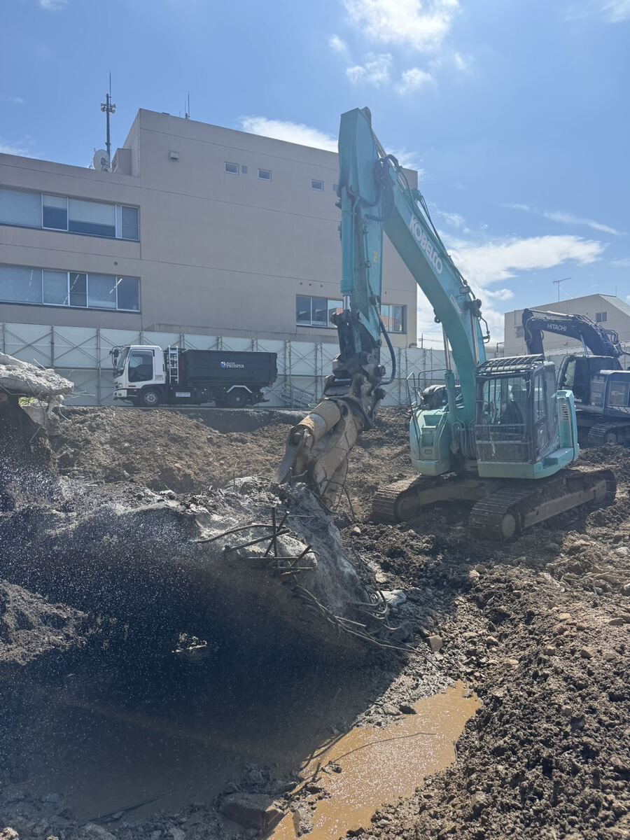 重機で基礎コンクリートを撤去し搬出する解体工事の現場